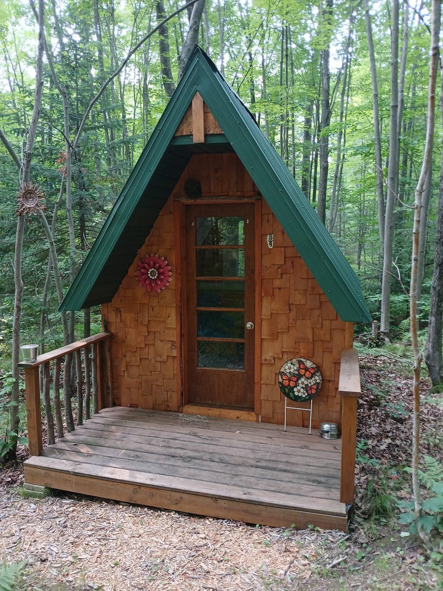 The Karner Blue A-frame cabin with its green roof, among the trees