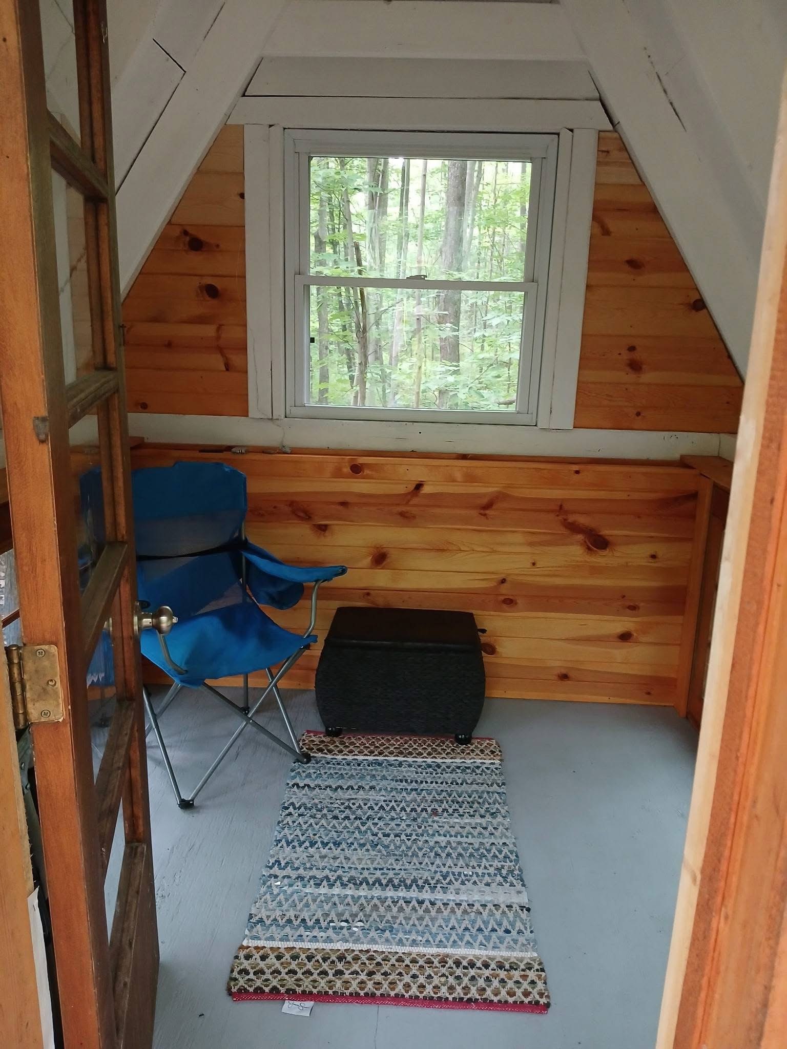 Inside an A-frame cabin loft with a window and cosy seating