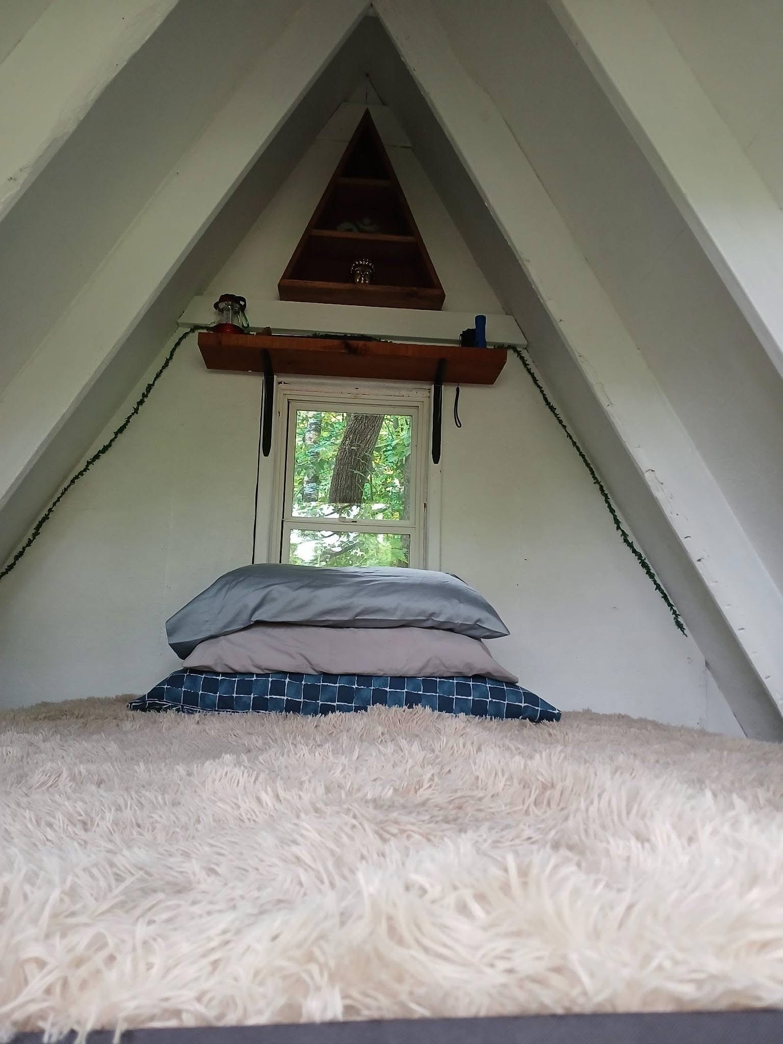 Inside a canvas A-frame glamping tent with a made bed