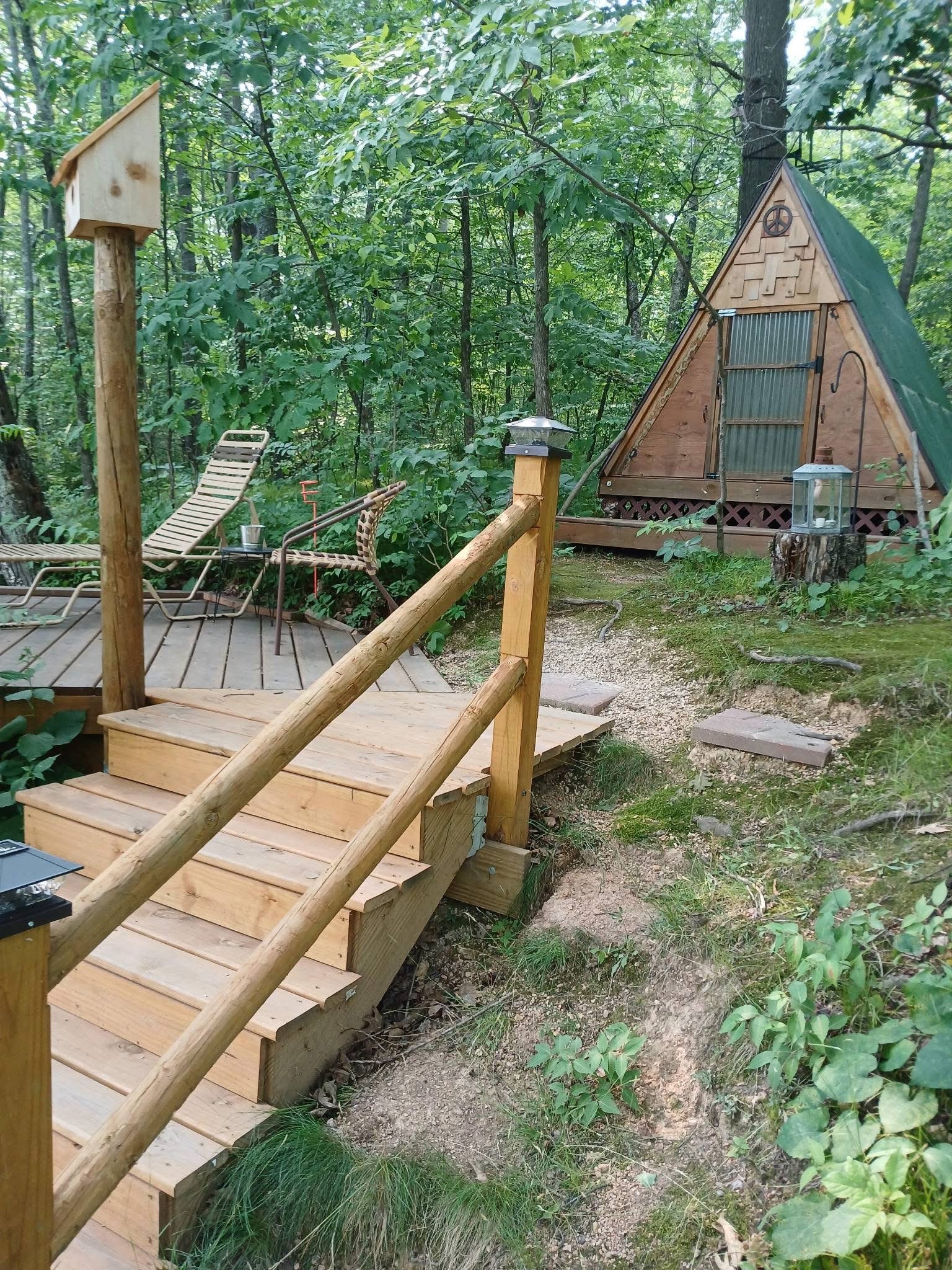 An A-frame glamping tent on a wooden deck in the meadow