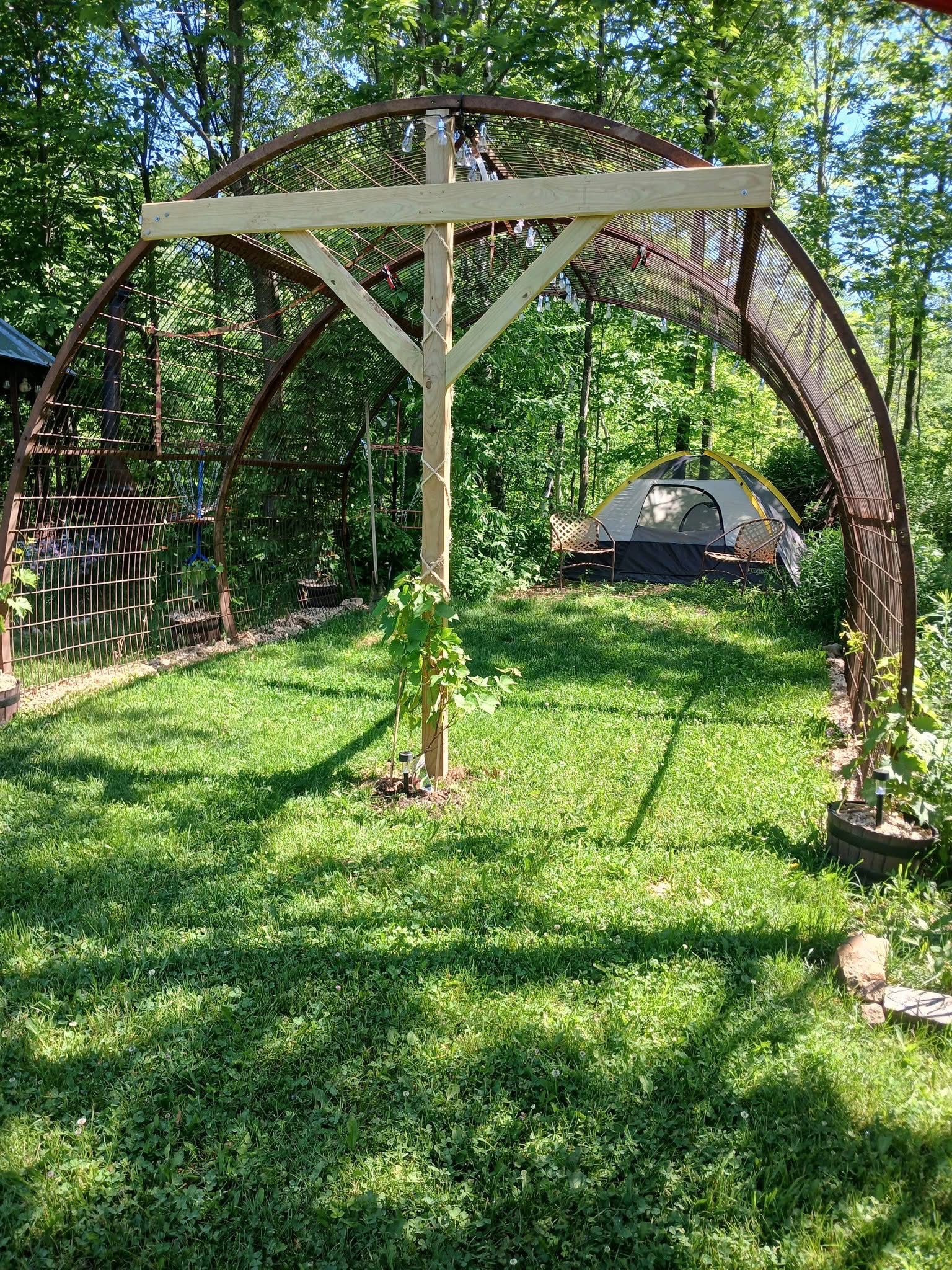 A tent pitched on the grass beneath the big iron arbor